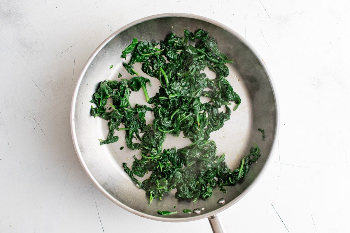 Wilted spinach cooked in a skillet.