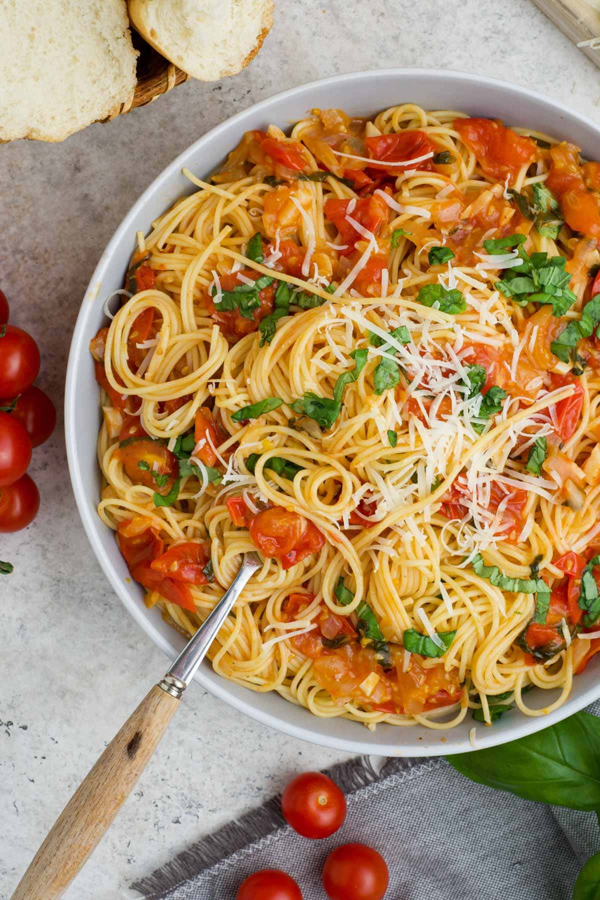 A large white platter with angel hair pasta and tomatoes.
