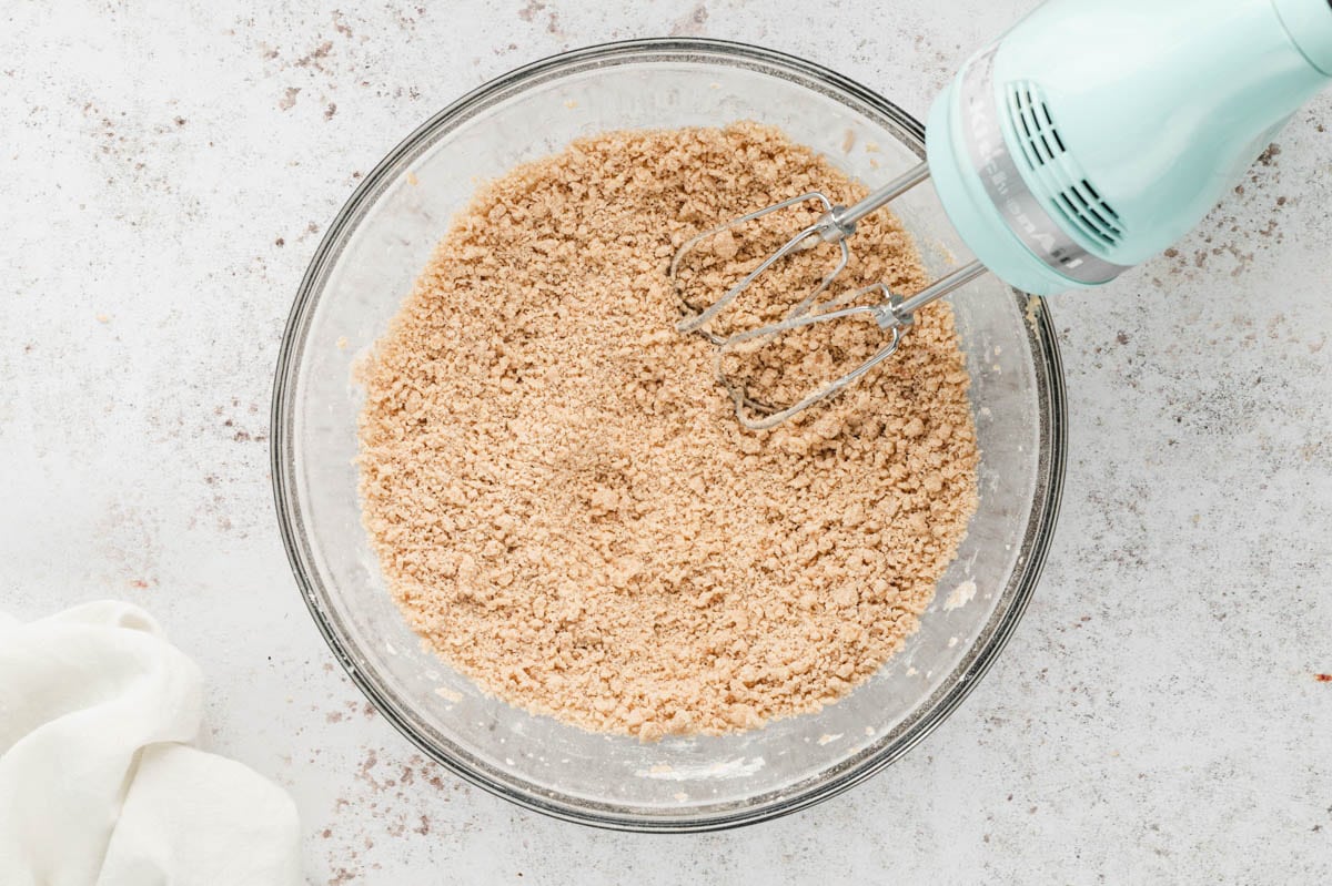 Crumbly dough in a glass mixing bowl with a mixer.