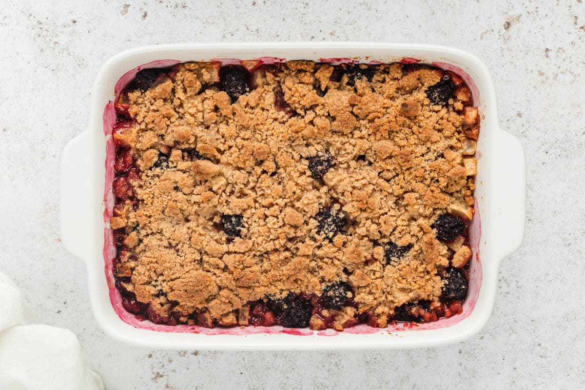 Baked apple blackberry crumble in a white baking dish.