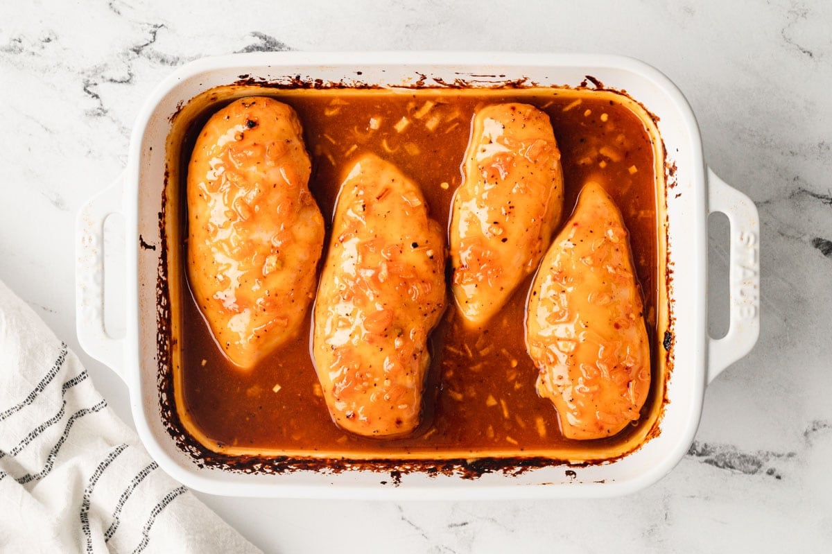 Baked chicken with apricot sauce in a white baking dish.