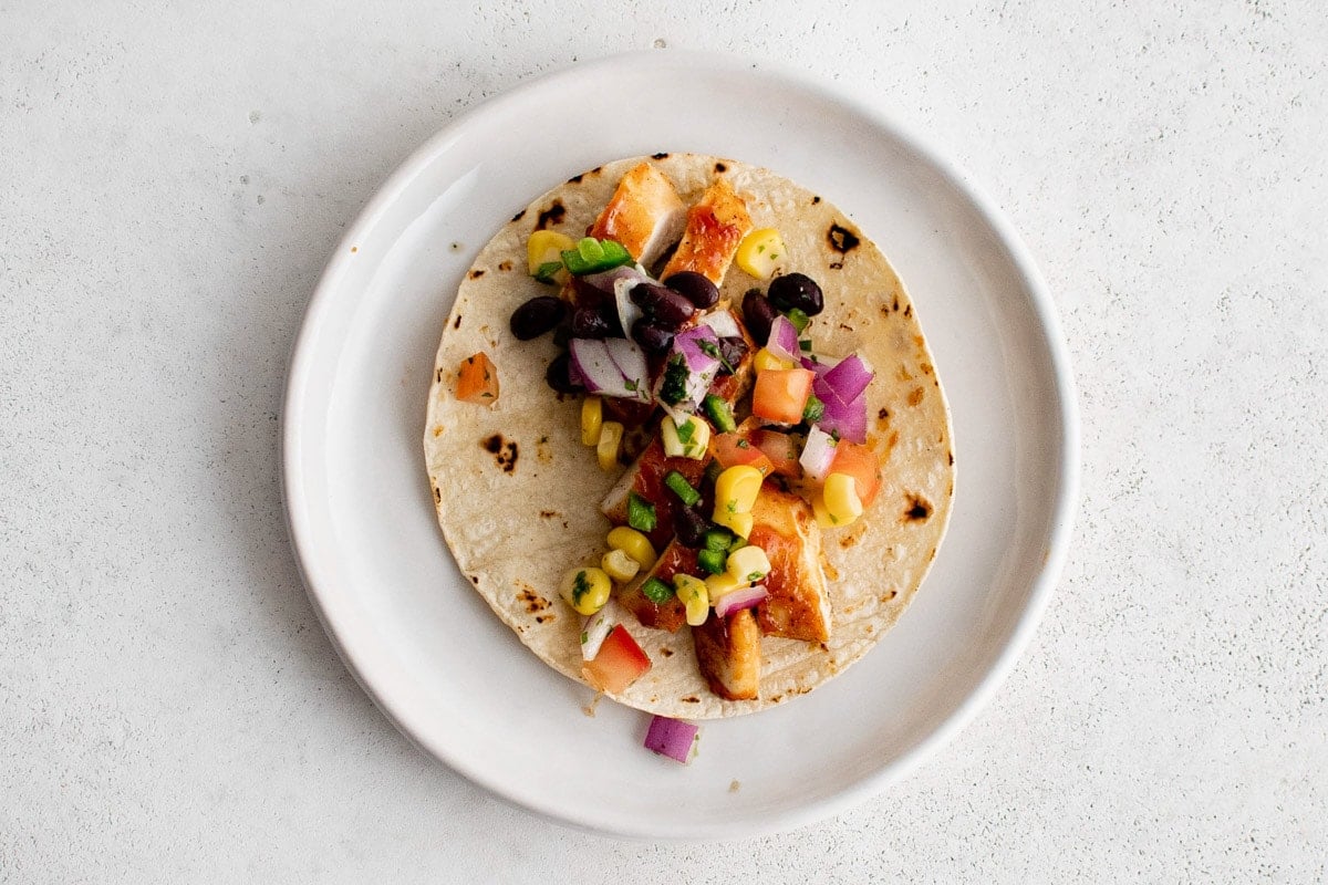 BBQ chicken taco with black bean salsa, corn, and a lime crema