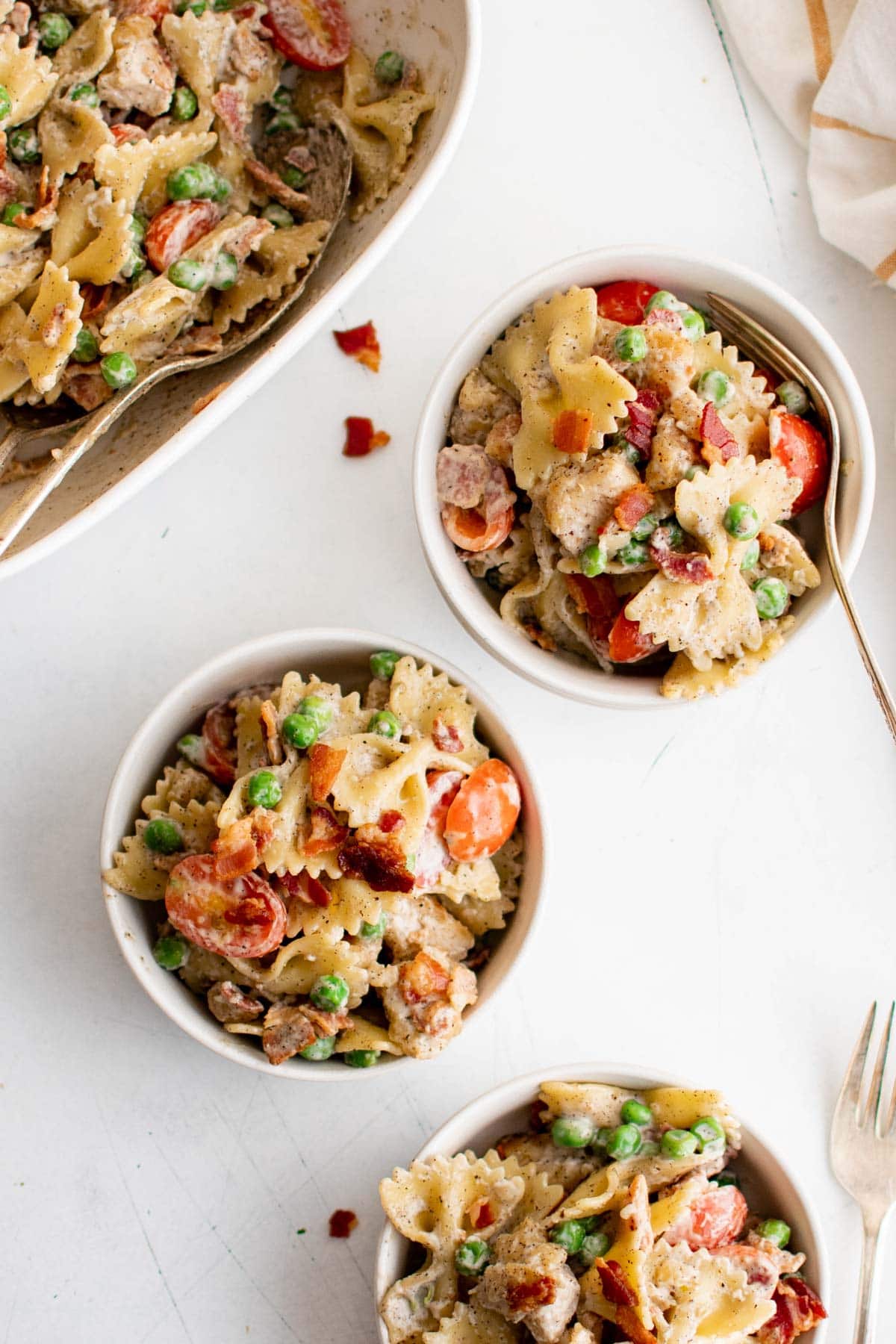 Bowls of chicken pasta salad with peas and tomatoes.
