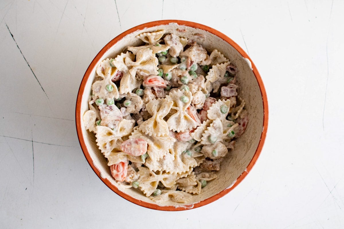 Pasta salad with peas and chicken in a white bowl. 