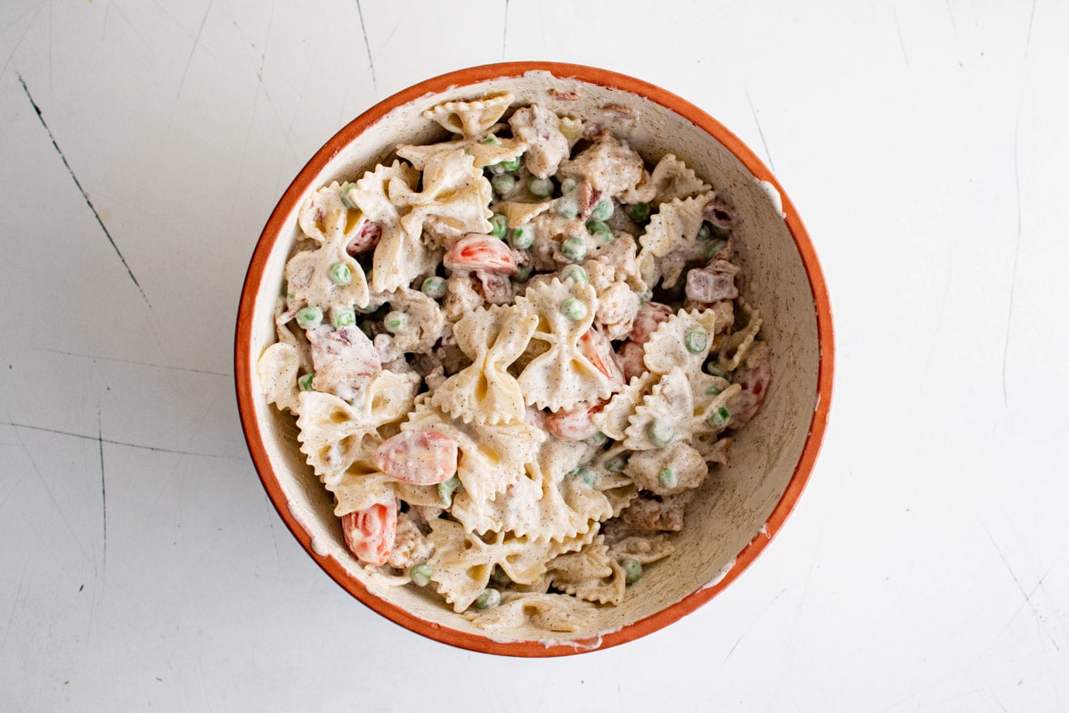 Pasta salad with peas and chicken in a white bowl.
