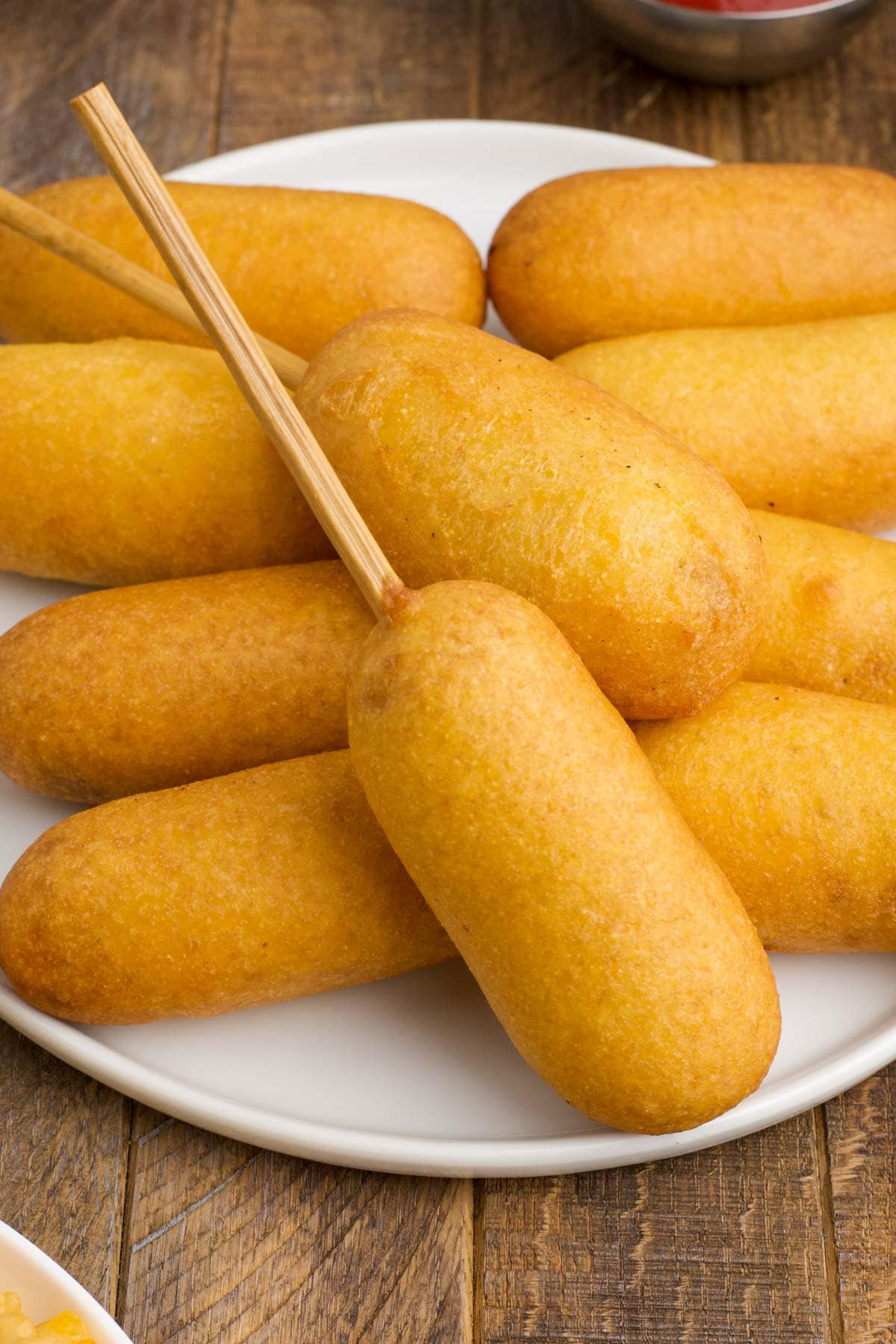 Corn dogs stacked on a white plate.