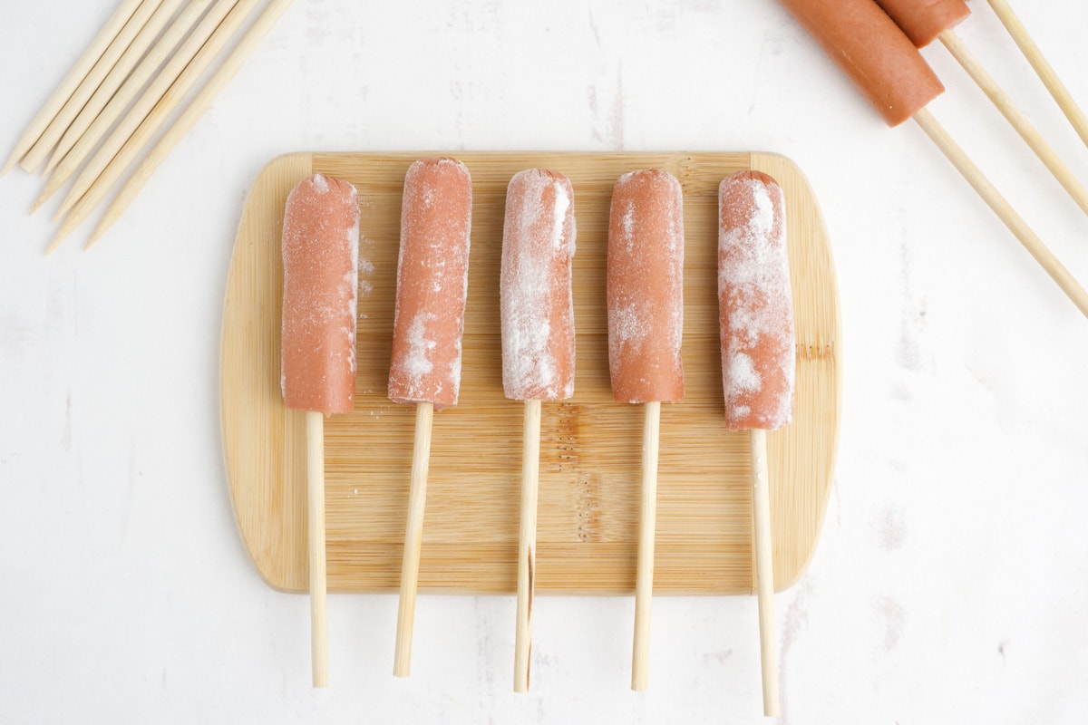 Hot dogs on sticks dusted with flour.