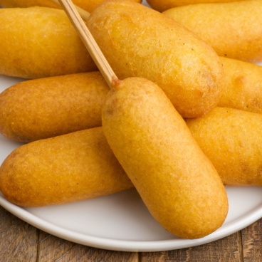 Corn dogs on a white plate.