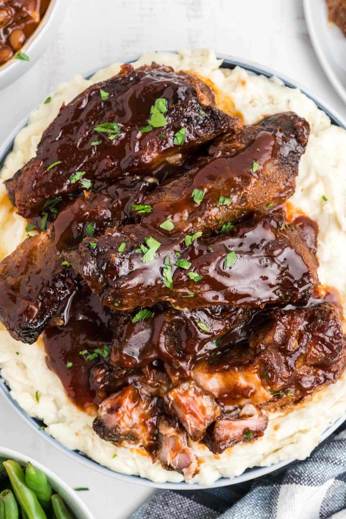 BBQ sauced boneless ribs plated over mashed potatoes.