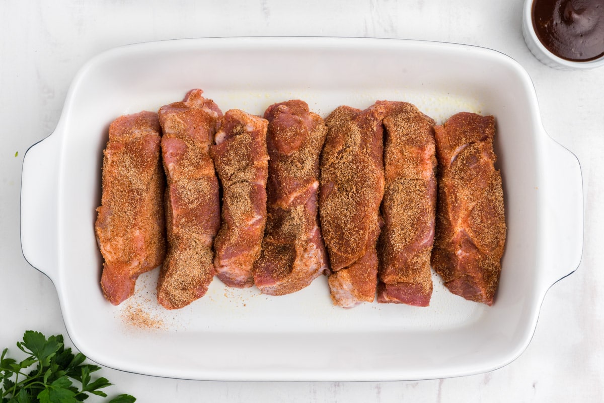 Boneless country ribs lined up in a white baking dish.