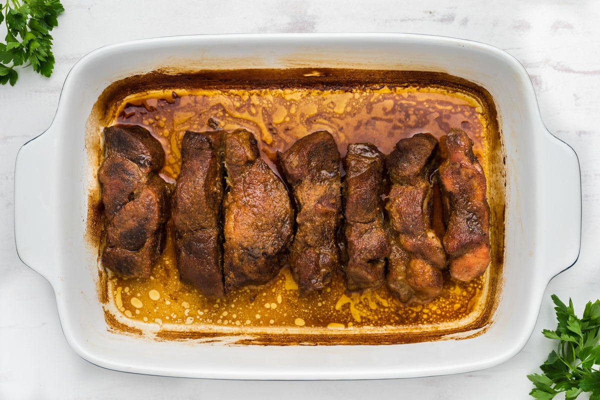 Baked boneless ribs in a white baking dish.