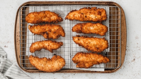 Fried chicken tenders on a baking rack.