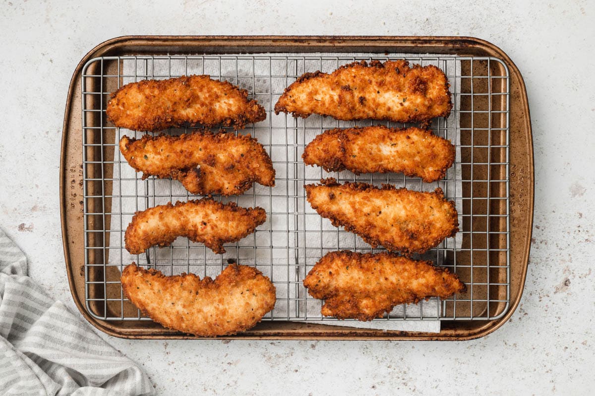 Fried chicken tenders on a baking rack.