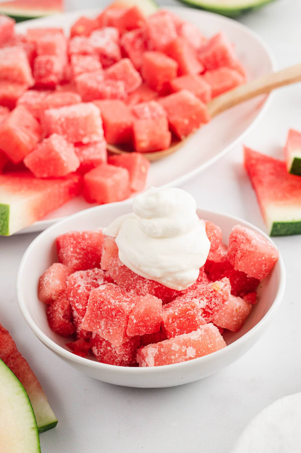 Frozen watermelon cubes in a bowl with whipped topping.