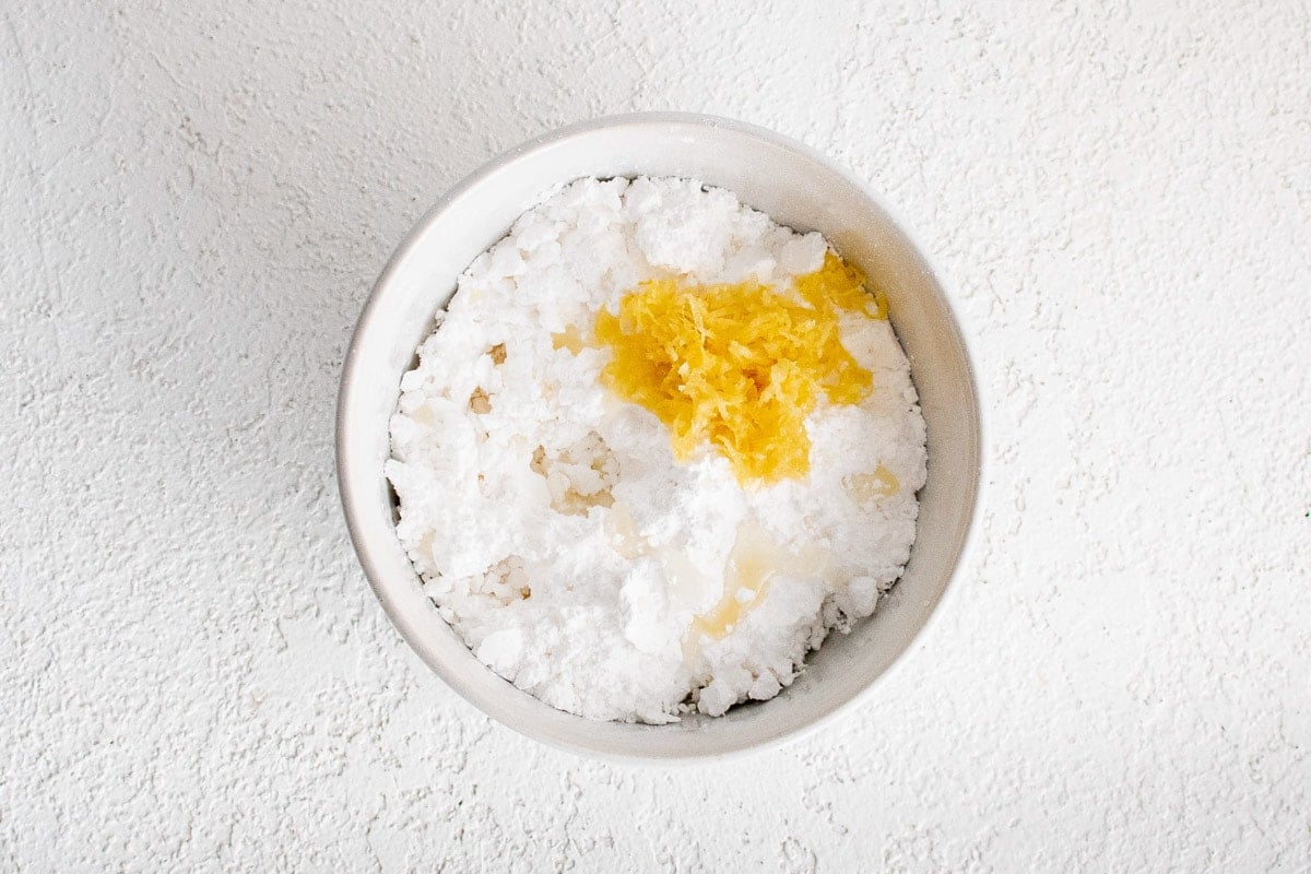 Powdered sugar, milk and lemon zest in a small dish.
