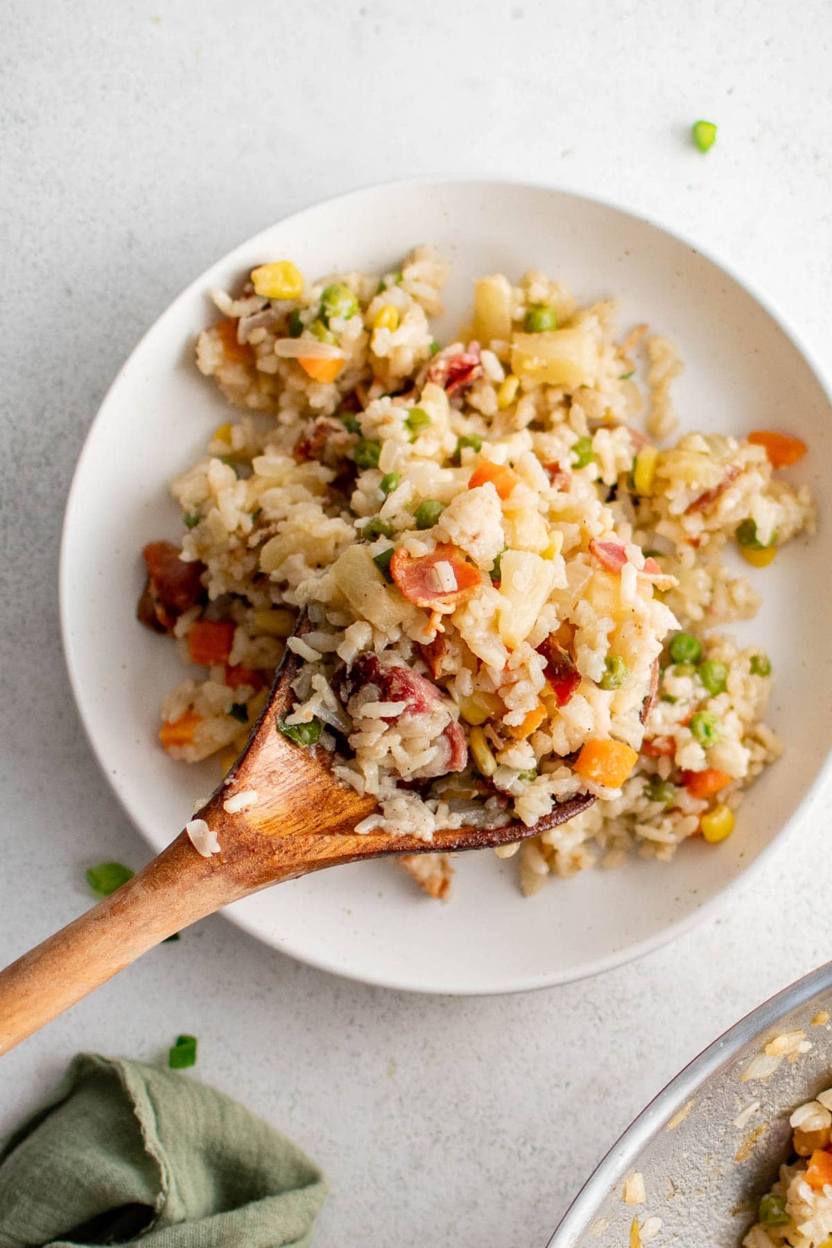 Small white plate with fried rice and a wooden spoon.