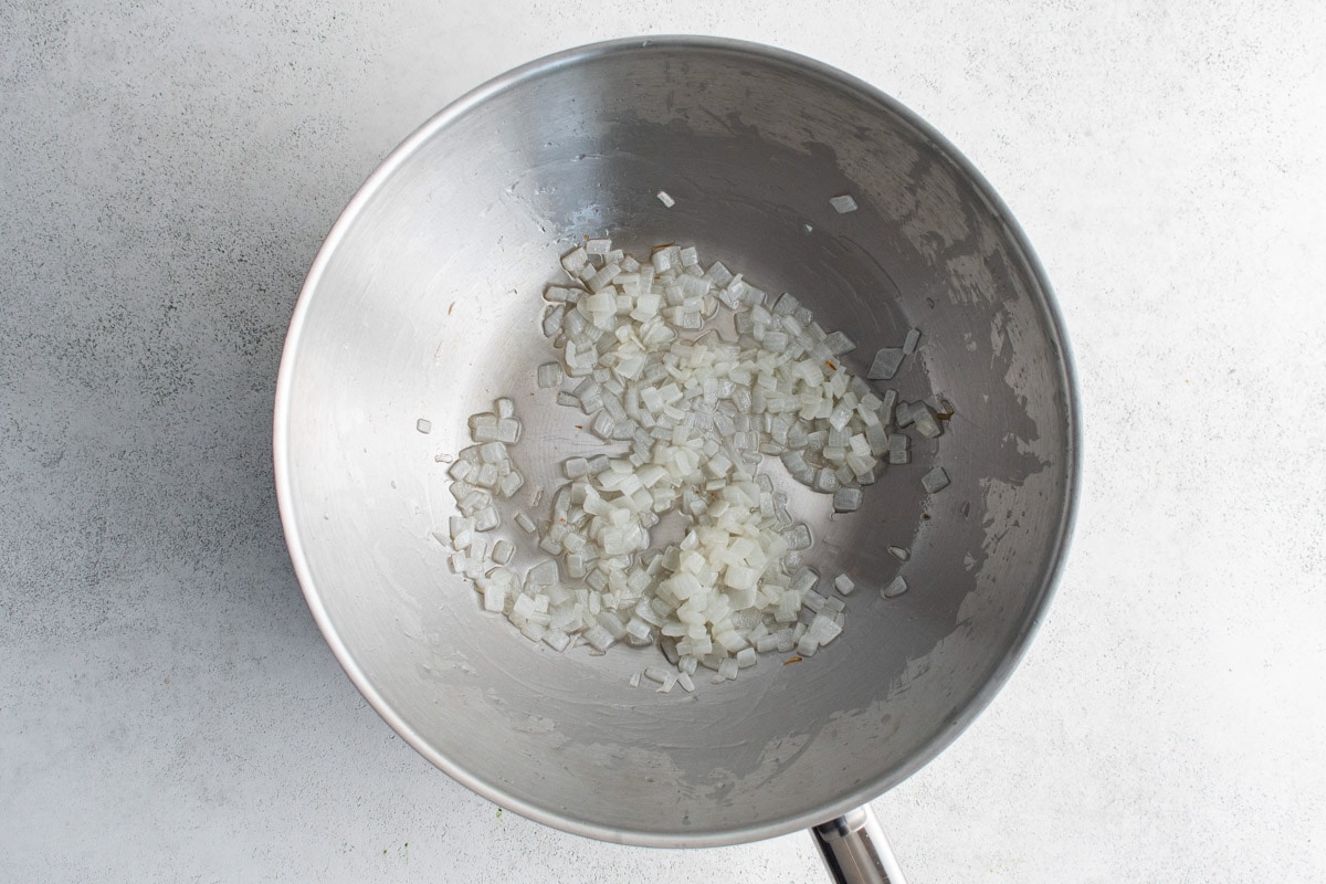 Diced onions cooking in a silver wok.