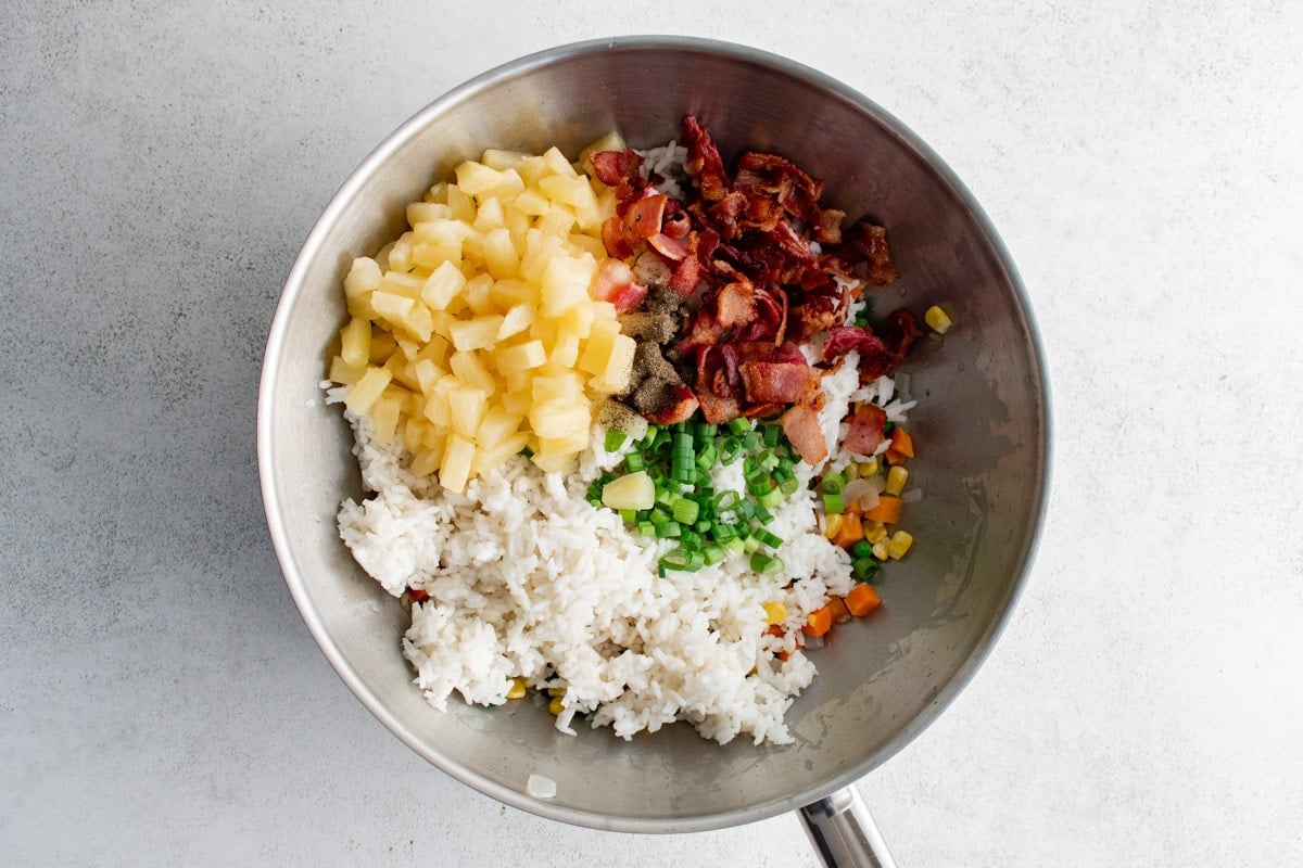 White rice, pineapple, bacon and vegetable in a wok.