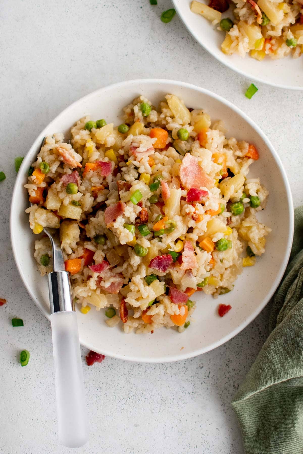 Bacon fried rice on a white plate with a fork.