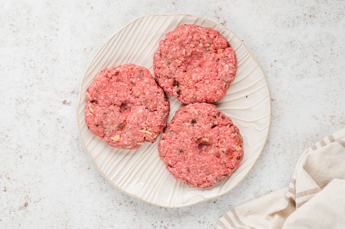 Formed hamburger patties on a white plate.