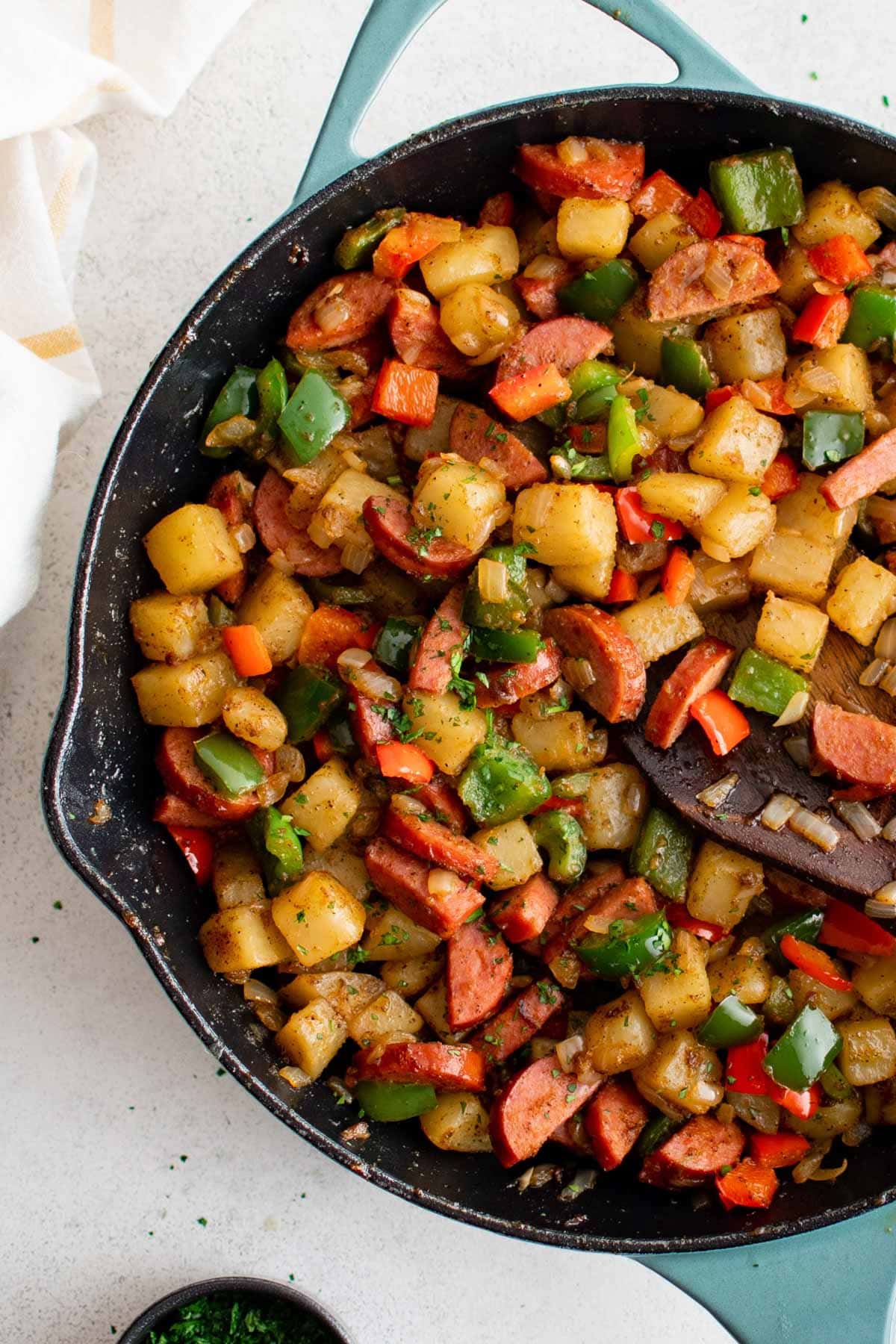 Large skillet filled with smoked sausage, potatoes, bell peppers and onions.