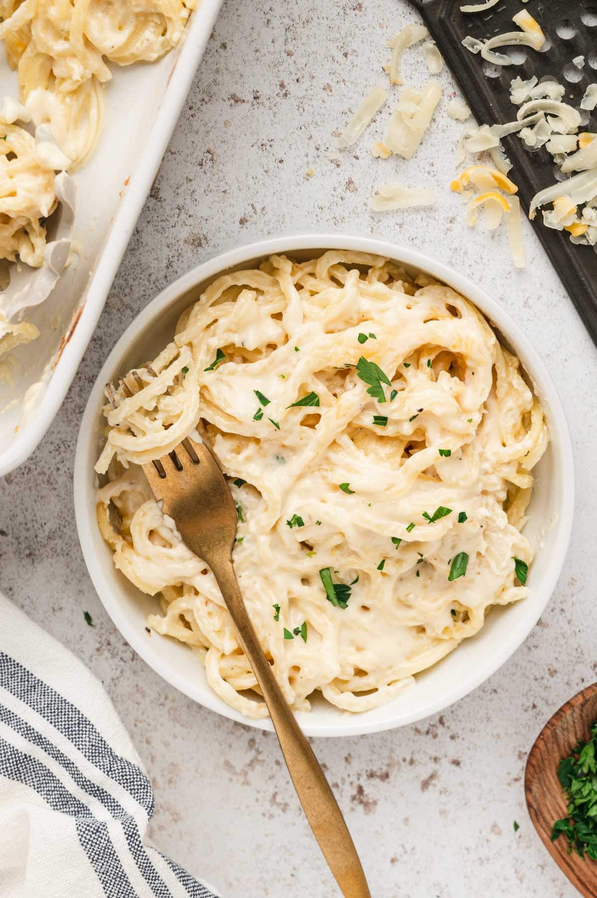 Small bowl with spaghetti in cheese sauce and a fork.