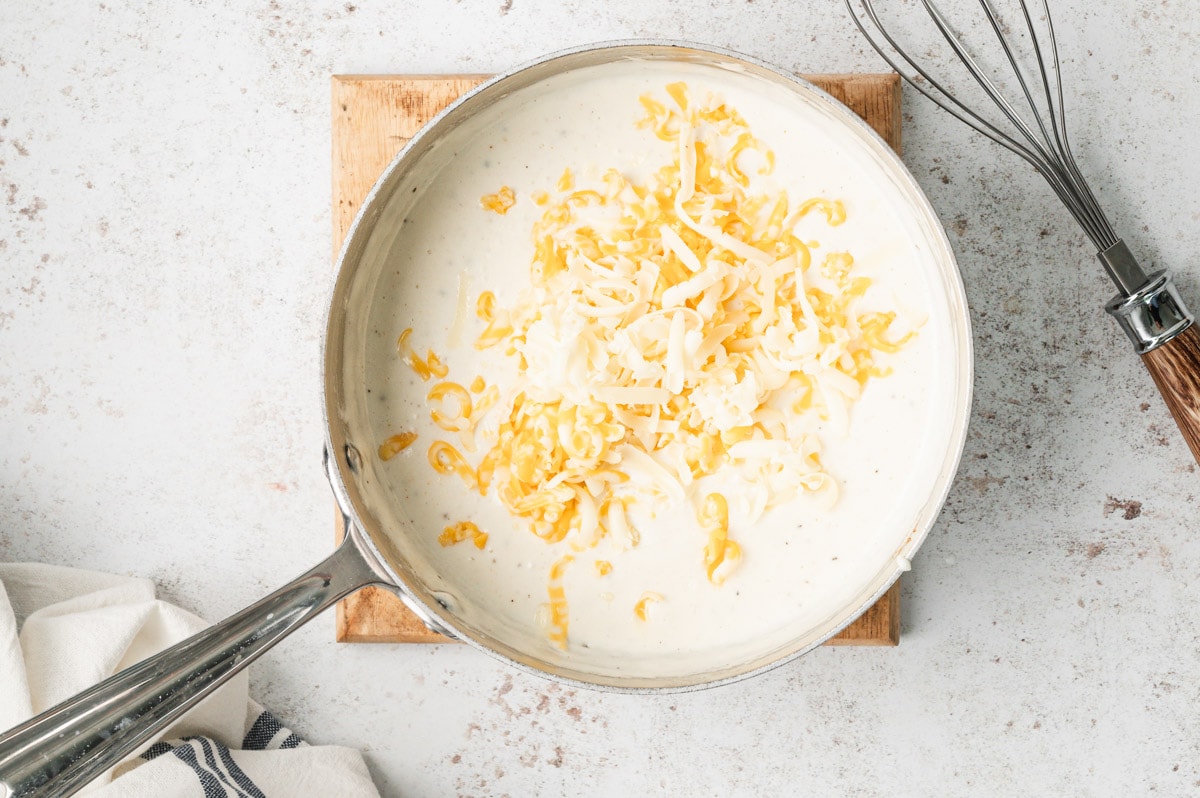 Cheese added to the white sauce in a saucepan.