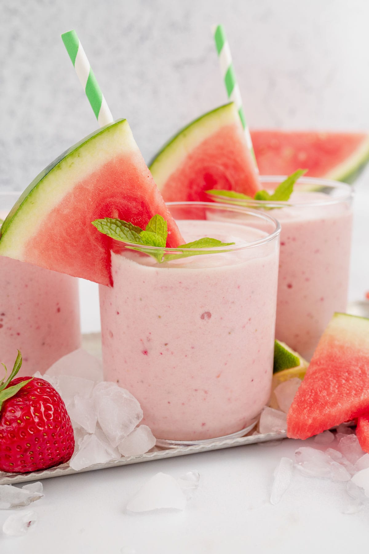 Watermelon smoothies in glasses with straws and slices of watermelon.