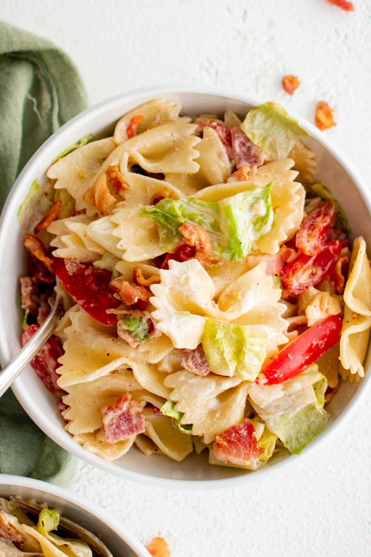 Bowl of pasta with bacon, tomatoes and lettuce.