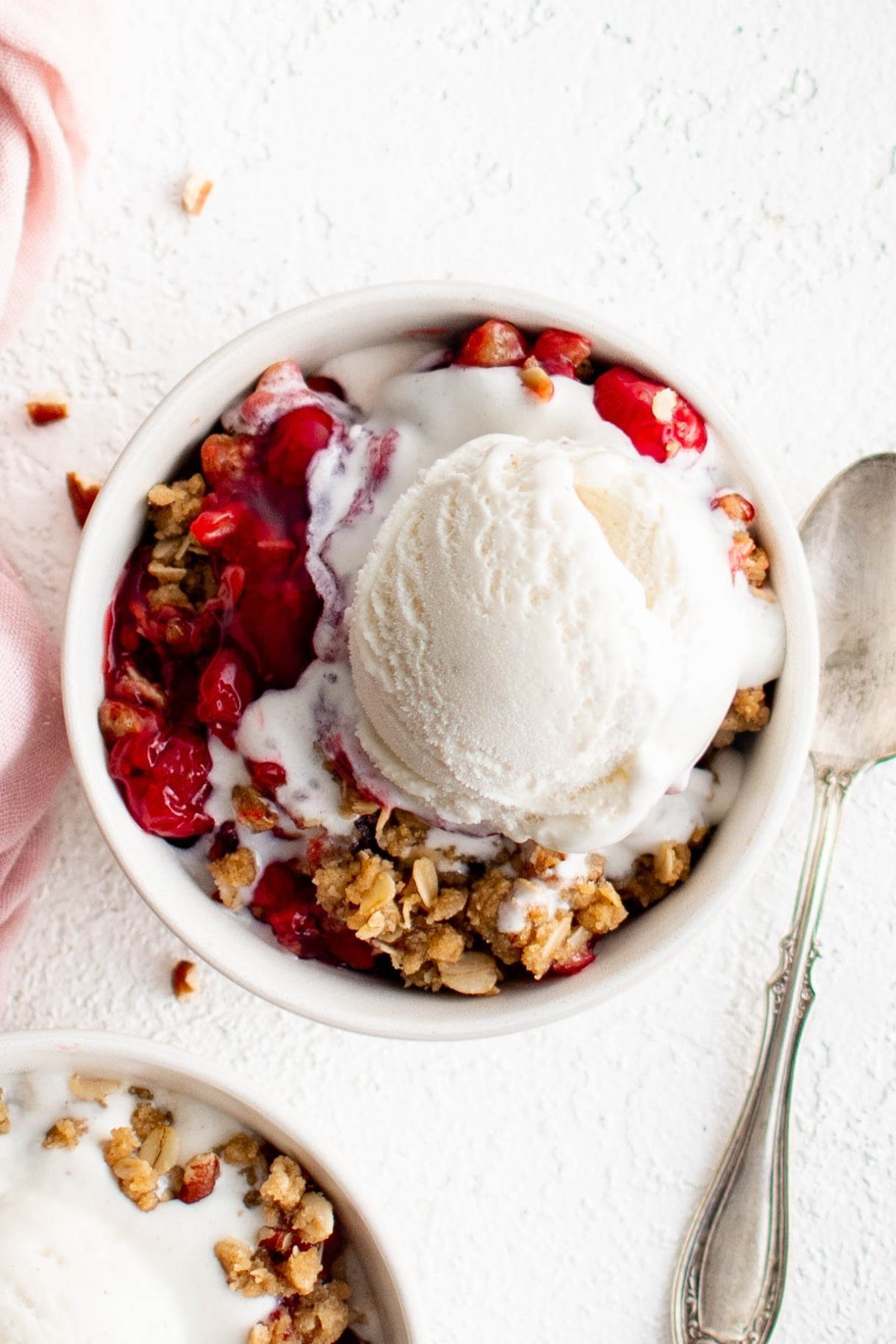 Cherry crisp with a scoop of vanilla ice cream in a small bowl.