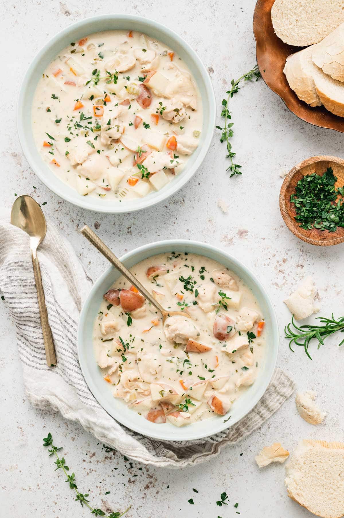 Light blue bowls with creamy chicken potato soup with vegetables and chicken.