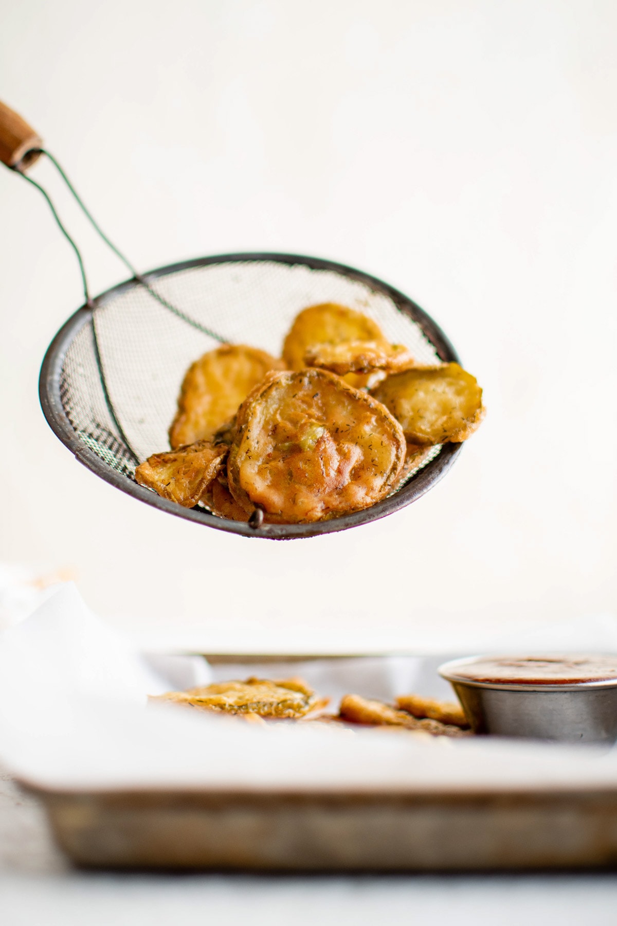 Fried pickles in a mesh sieve after frying.