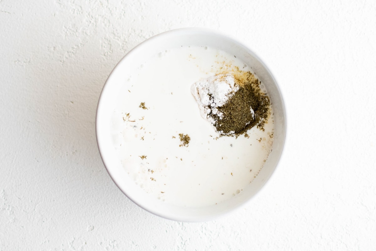 Milk, flour and seasonings in a small white bowl.