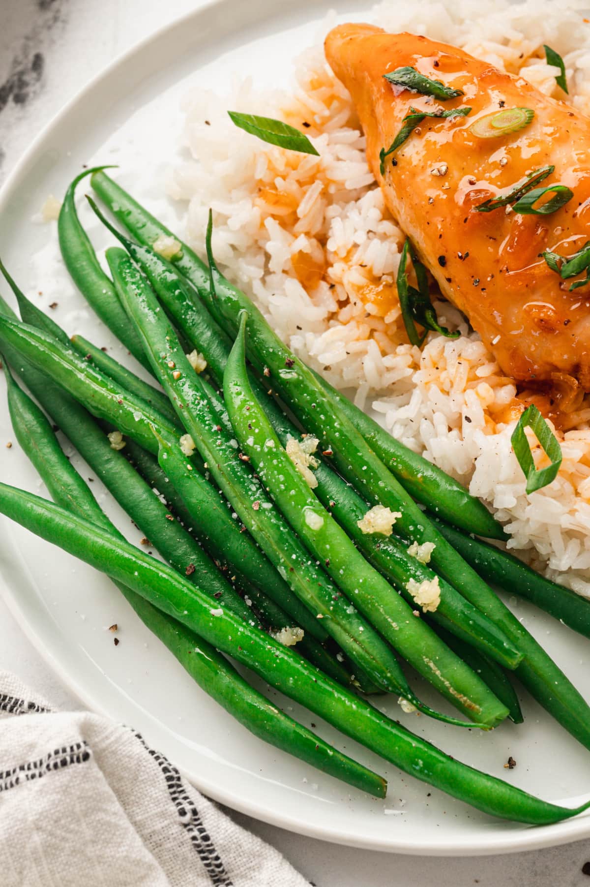 Green beans, rice and apricot chicken breast on a plate.