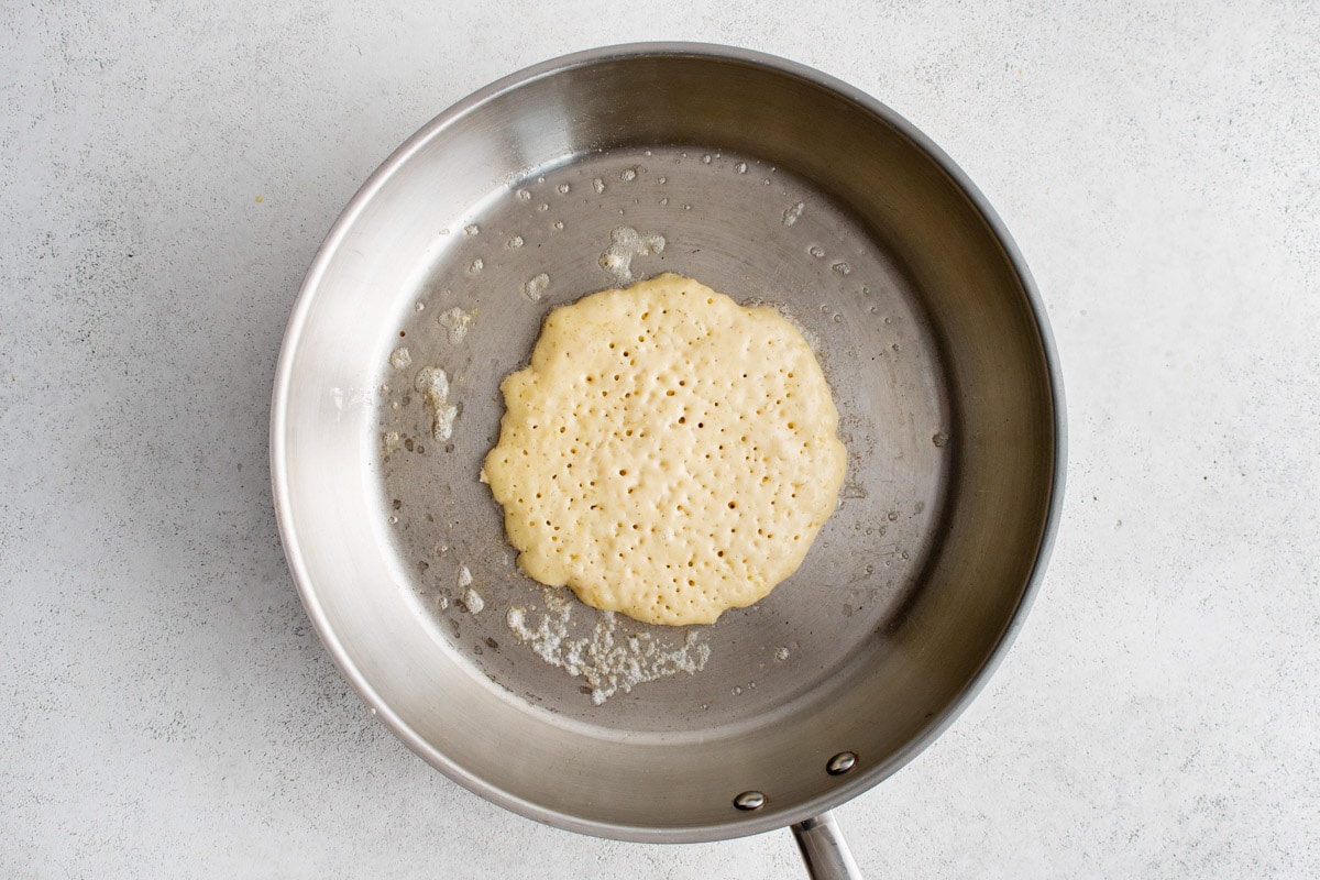 Pancake in a skillet, battar is beginning to form bubbles.
