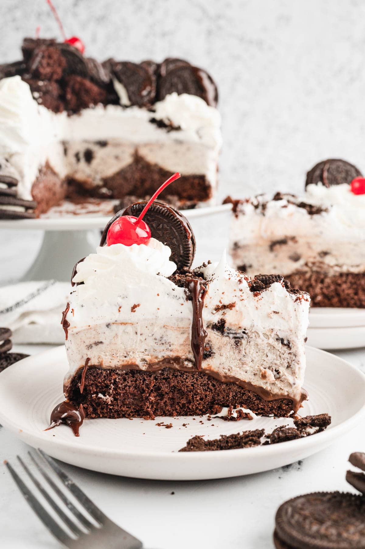 Slice of ice cream cake with oreos on a plate.