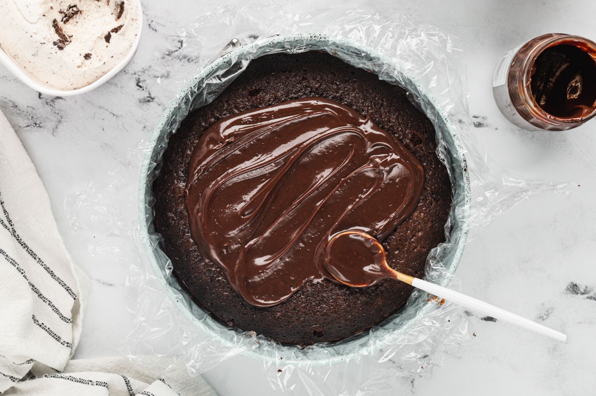 Chocolate cake in a round pan topped with hot fudge.
