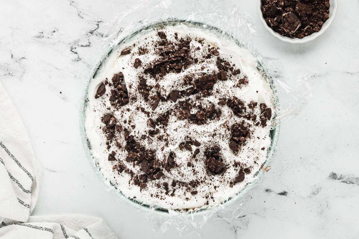 Round cake pan with whipped topping and crushed Oreos.