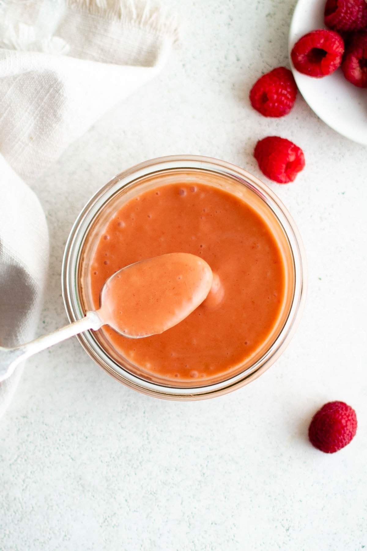 Raspberry vinaigrette dressing in a jar with a spoon.