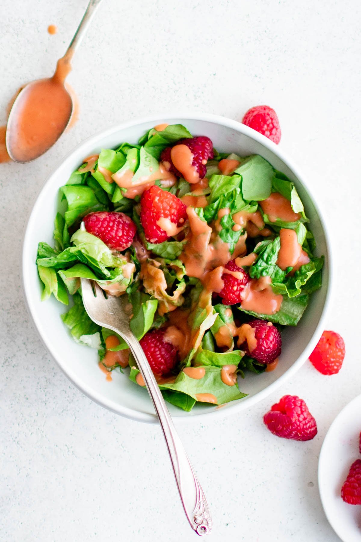 Salad with raspberries, and raspberry vinaigrette and a fork.
