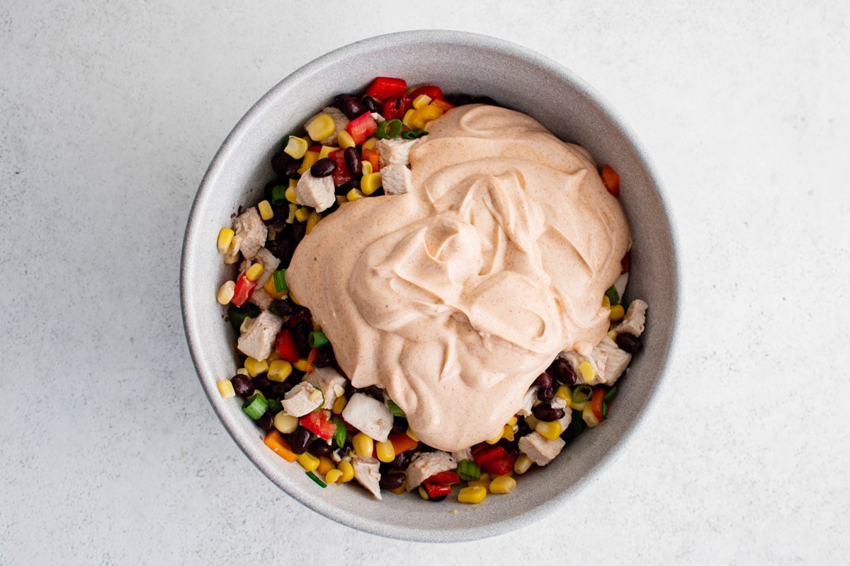 Chicken, black beans and veggies in a bowl with a creamy southwest dressing poured on top.