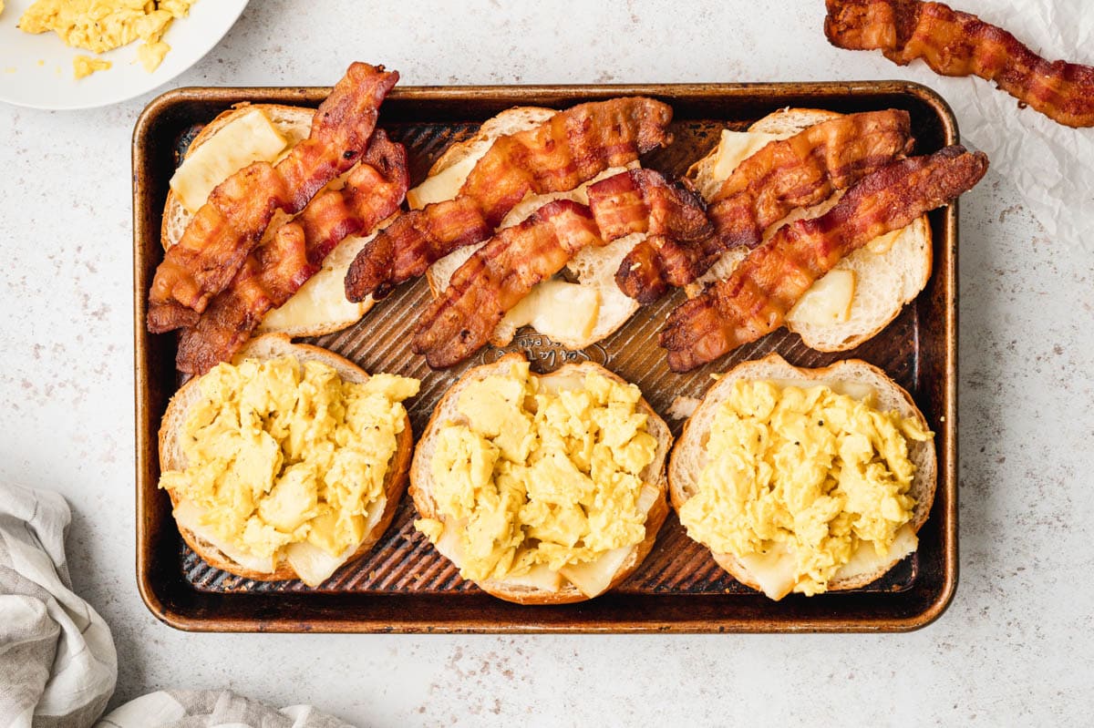 Sheet pan, croissant halves topped with cheese, bacon and scrambled eggs.