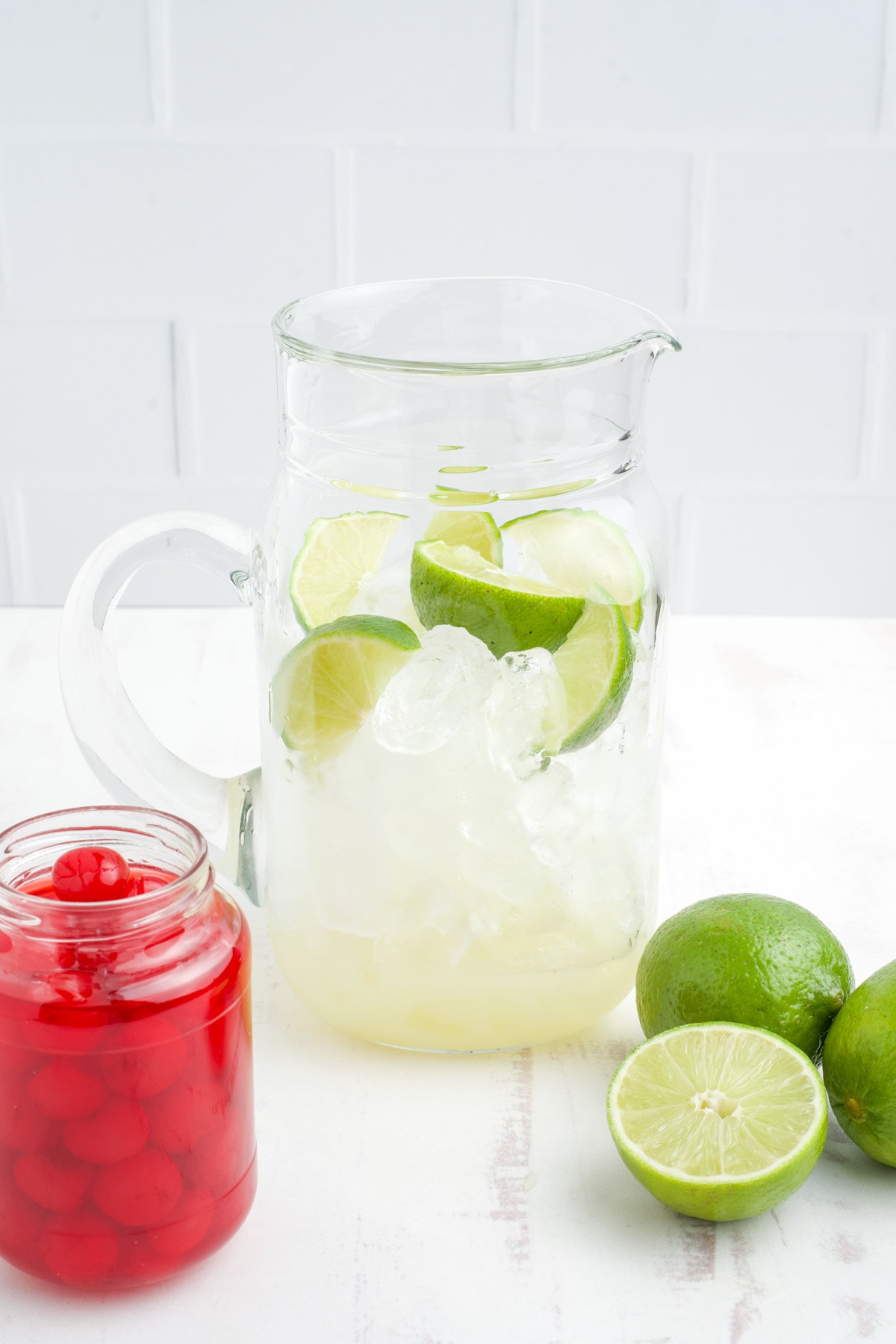 Limes and lime juice in a large pitcher.