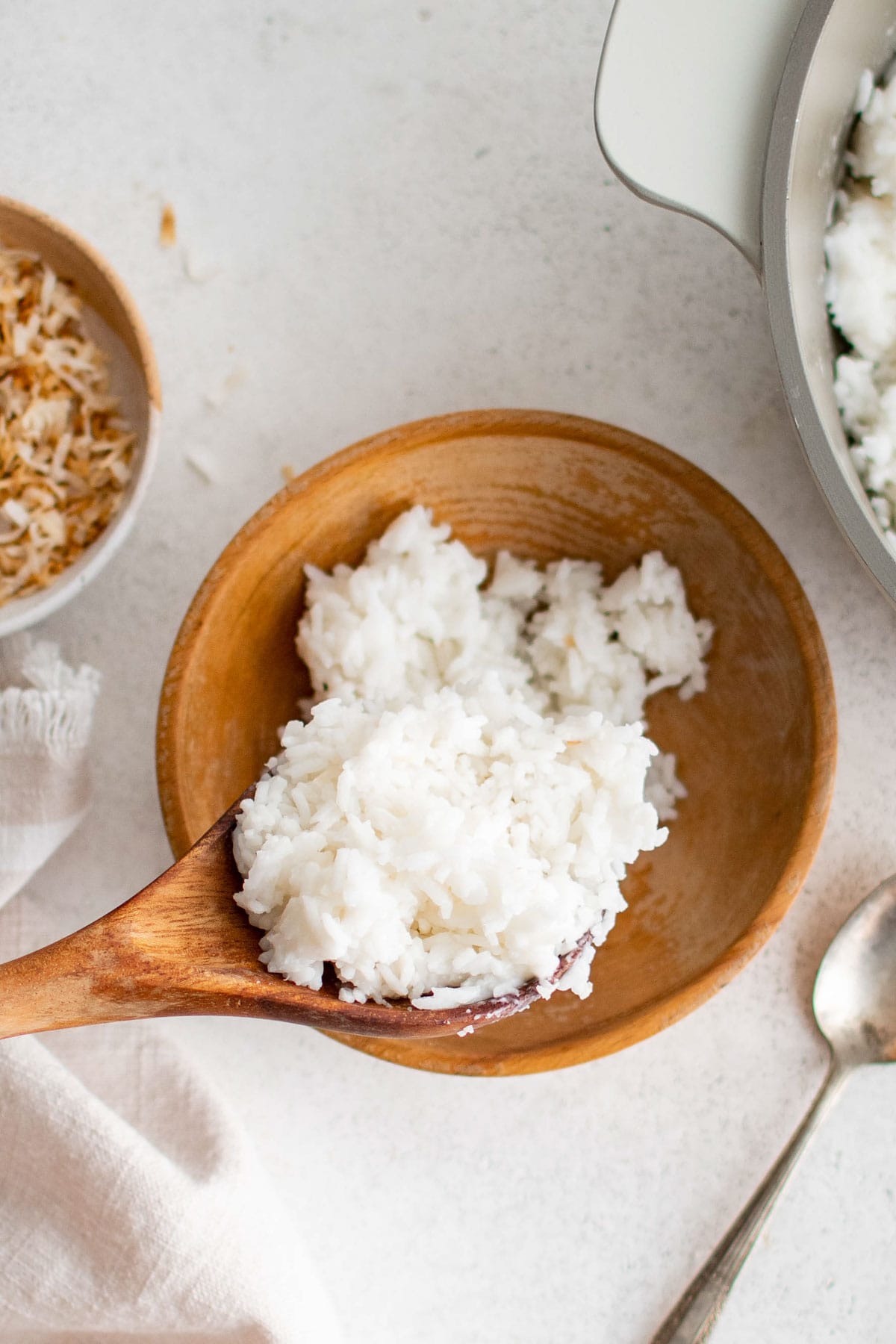 Serving rice into a wood bowl with a wooden spoon.