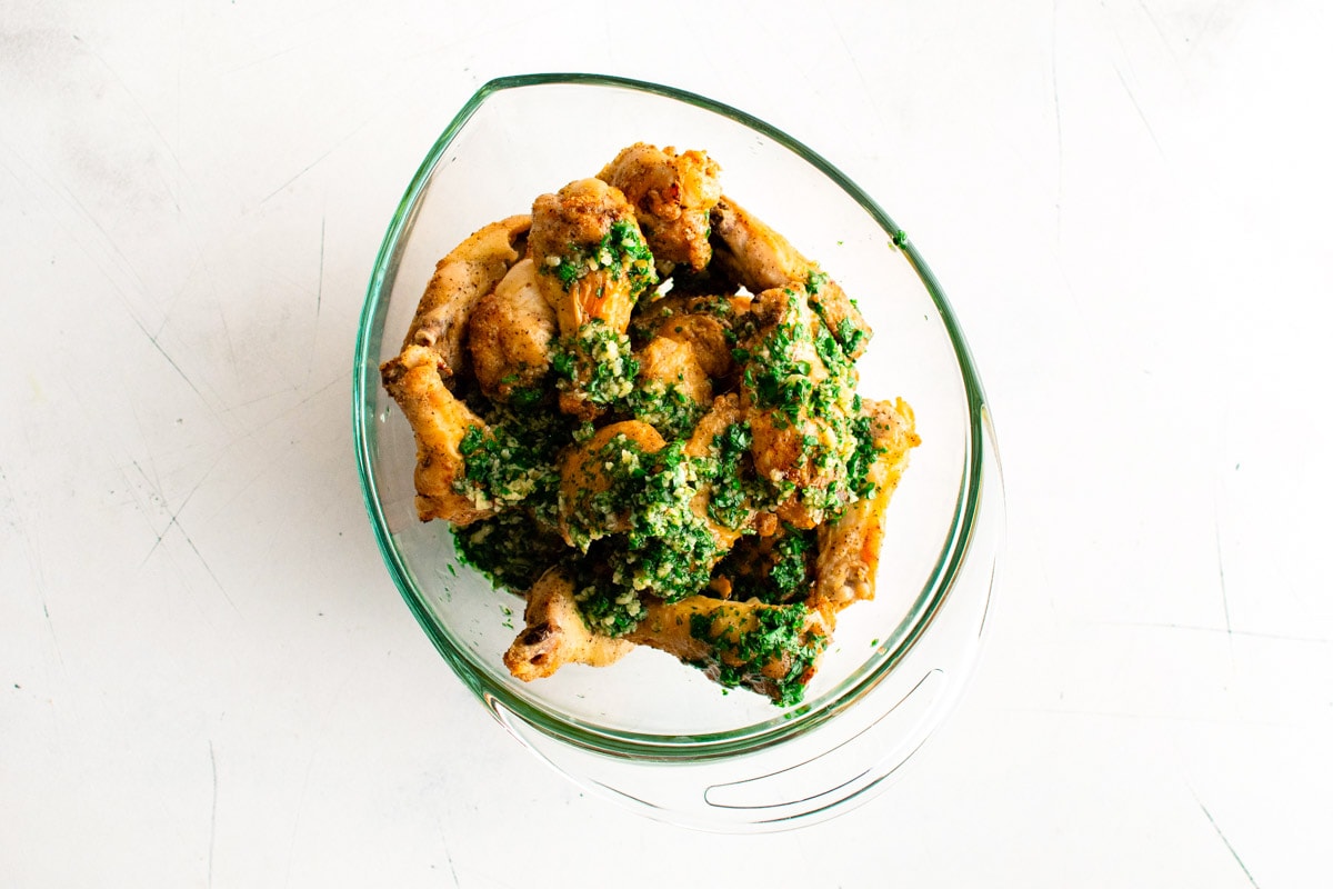 crispy chicken wings in a bowl with parsley and melted butter with garlic.