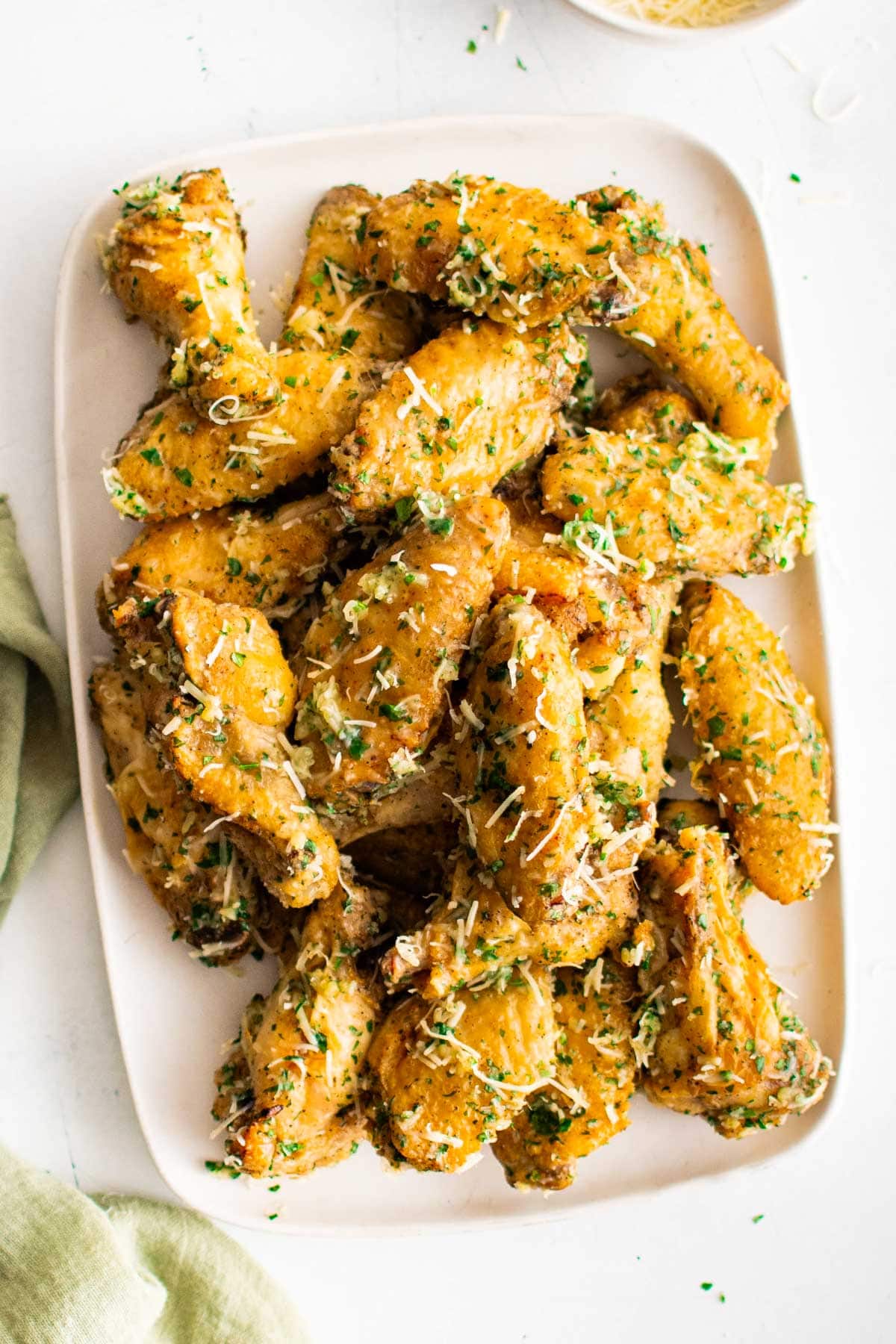 Stacks of garlic parmesan wings on a white platter. 