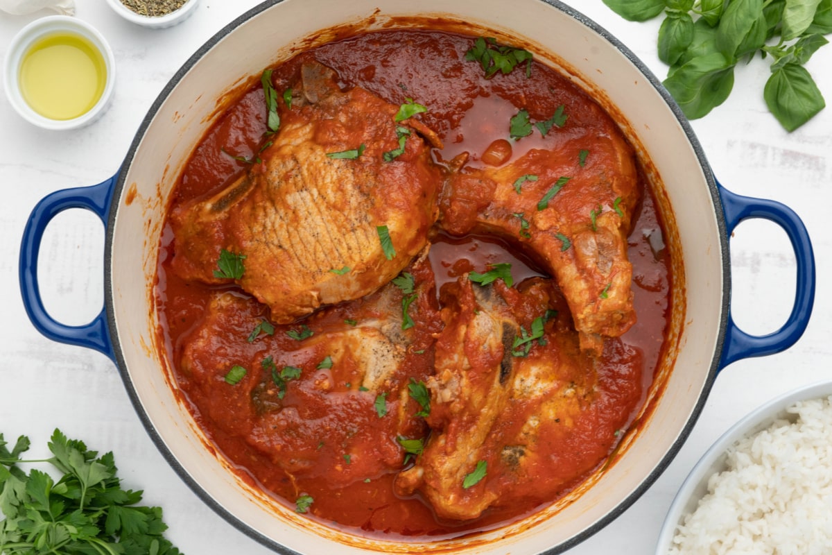 Pork chops in tomato sauce in a dutch oven.