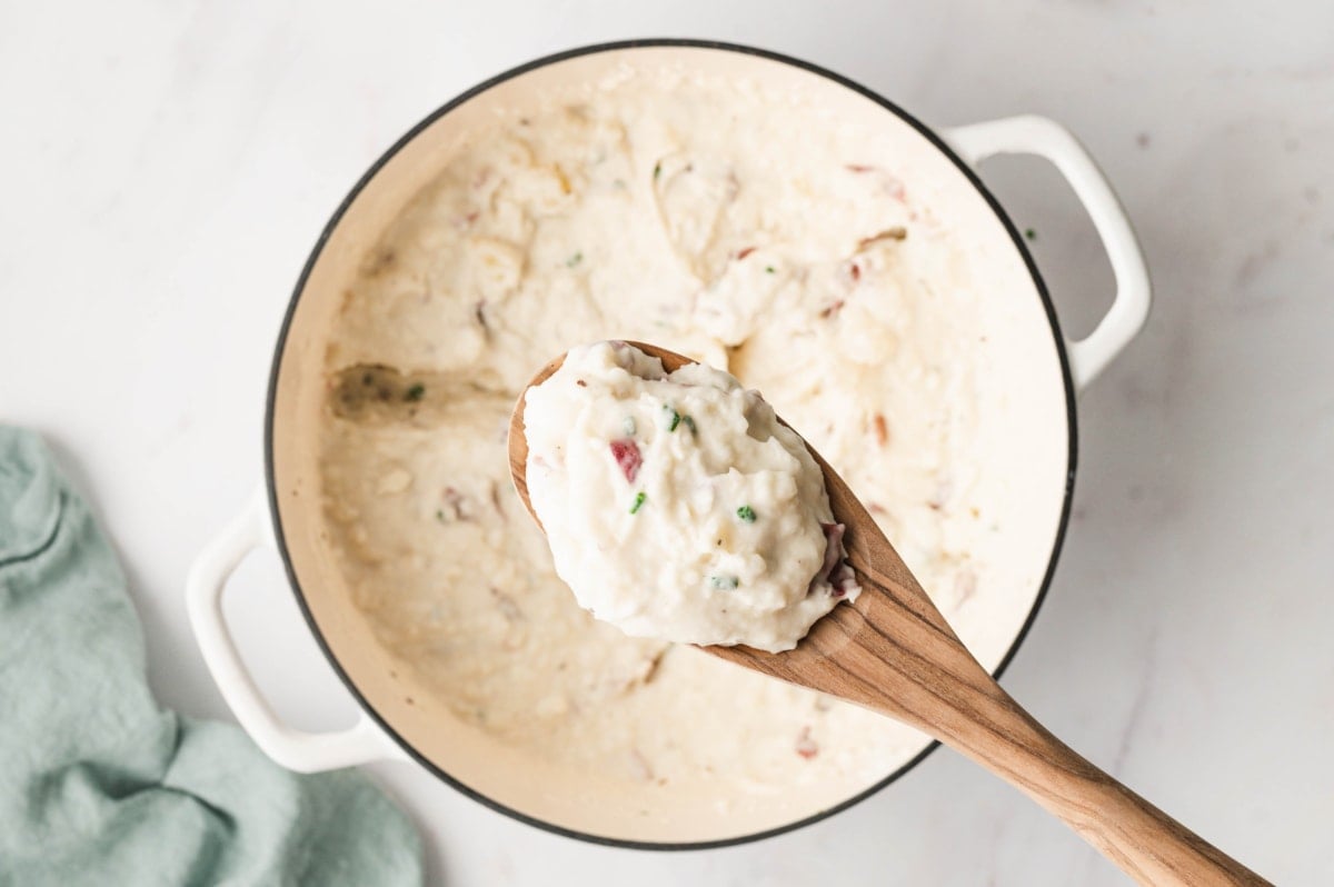 Creamy red skinned mashed potatoes and a wooden spoon.