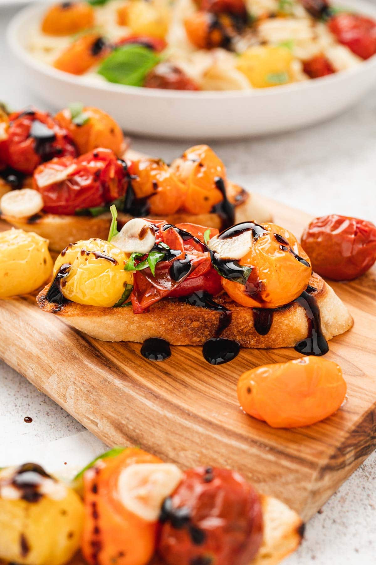 Roasted tomatoes on top of a slice of toasted baguette with a balsamic drizzle.