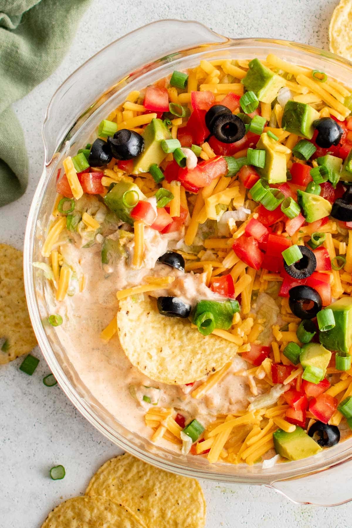 Taco dip and a tortilla chip in a round dish.